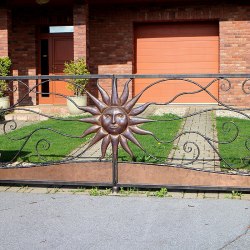 Kovaná brána s tepaným slnkom pri rodinnom dome