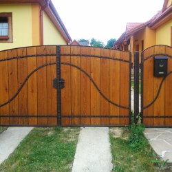 Plná kovaná brána s drevom pri rodinnom dome na vidieku