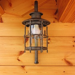 Ručne kovaná nástenná lampa pri vstupe do súkromnej chalupy v horách
