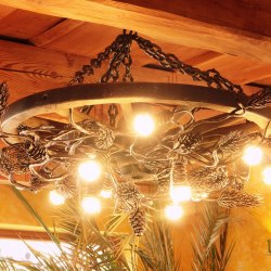 Umelecké kované svietidlo do interiéru s prírodným motívom stromu sosny